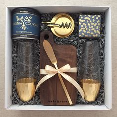 an open gift box containing two bottles of wine and a corkscrew with a ribbon