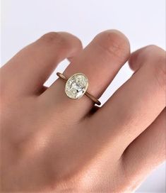 a woman's hand with a diamond ring on top of her finger, showing the center stone