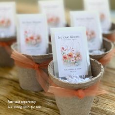 small pots with cards in them sitting on a wooden table next to each other and tied with orange ribbon