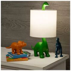 two dinosaur figurines sitting on top of a table next to a white lamp