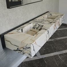 a marble bench sitting in the middle of a room next to a wall with a mirror on it