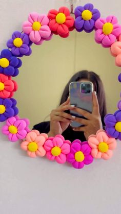 a woman taking a selfie in front of a mirror with flowers on the frame