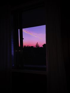 an open window at night with the sun going down in the sky and trees outside