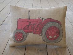 a red tractor pillow sitting on top of a wooden floor