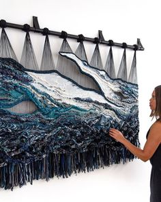 a woman standing next to a piece of art that is made out of yarn and thread