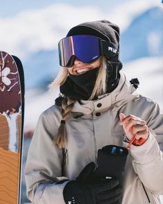 a woman wearing goggles and holding a snowboard