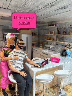 two mannequins sitting at a kitchen counter with a laptop computer in front of them