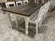 a wooden table surrounded by white chairs in a room