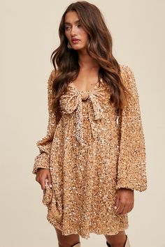 -Color: Gold -Front tied sequin long sleeves dress -Stretched -V-neck with front tie -Long puff sleeves with elastic cuffs -Open back with adjustable tie string Zipper on back waist -Finished with clean hem -Lined -Imported -Content: 97% Polyester 3% Spandex -Model is 5' 7" 31-24-35 and wearing a size Small Long Sleeve Mini Dress Lulus, Long Sleeve Formal Dress Short Lulus, Sequin Flutter Sleeve Dress, Long Sleeve Sequin Fringe Dress, Sequin Dresses Short Long Sleeve, Long Sleeve Tulle Mini Dress, Affordable Flirty Mini Dress For Fall, Boho Long Sleeve Homecoming Dresses, Gold Sequined Dress With Sleeves