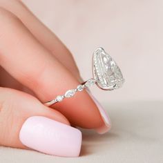 a woman's hand with a ring on it and a pink manicured nail