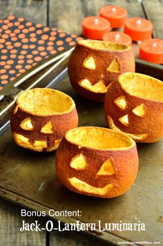 four carved pumpkins sitting on top of a tray with candles in the shape of jack - o'lantern faces