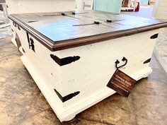 an old chest is painted white and has black paint on the top with brown trim