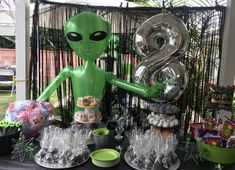 an alien themed birthday party with balloons, candy and candies on a black table