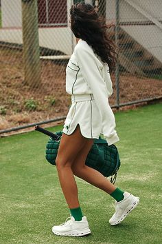 a woman holding a tennis racquet on top of a grass covered tennis court