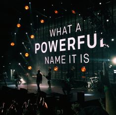 a group of people standing on top of a stage with lights in the dark behind them