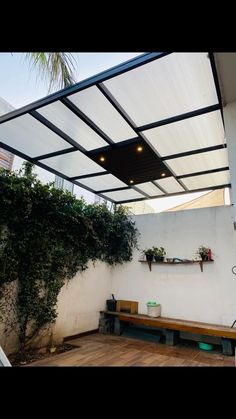 an outdoor patio with wooden flooring and plants on the wall, under a white awning