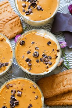 four cups filled with peanut butter and chocolate on top of a table next to cookies