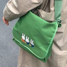 a person carrying a green bag with rabbits on it