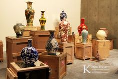 many different vases are on display in an art gallery with wooden crates around them