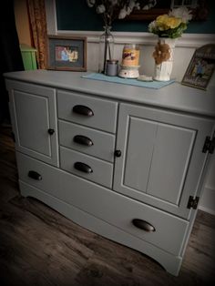 a gray dresser with drawers and pictures on top