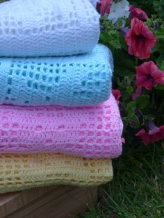 four crocheted towels stacked on top of each other in front of some flowers