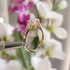 a close up of a diamond ring with flowers in the background