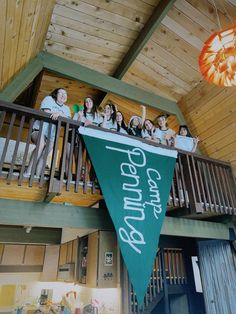 a group of people standing on top of a green flag hanging from a wooden ceiling