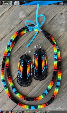 two pieces of beaded jewelry on a wooden floor with blue ribbon and beads around it