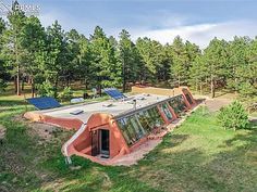 an aerial view of a house with solar panels on the roof and trees in the background