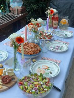 a table topped with plates and bowls filled with food next to candles on top of each plate