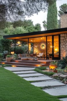 a modern home with stone steps leading to the front door and covered patio area, surrounded by greenery