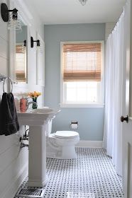 a white toilet sitting next to a sink in a bathroom under a window with sheer curtains