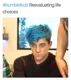 a man with blue hair is looking at the camera