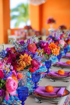 the table is set with colorful flowers and place settings