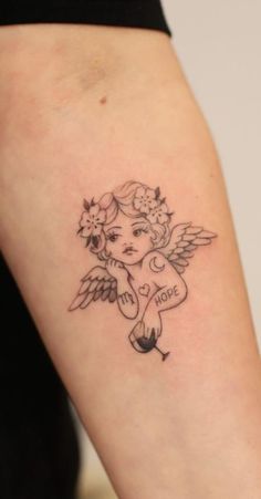 a small tattoo on the arm of a girl with an angel and flowers in her hair