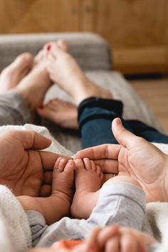 two people are laying on a bed with their feet in the air while holding hands