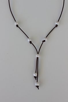 This cool leather and pearl necklace comes in brown or black rolled leather with 7 round white freshwater 8 mm pearls. Very cool and casual just slip the necklace over your head and adjust the sliding pearl if necessary. Wear as high fashion or with your favorite jeans this leather and pearl lariat is sure to be a favorite. Handmade in my St. Augustine jewelry studio. Total length is 32 inches. White Adjustable Lariat Necklace With Pearl Charm, White Adjustable Lariat Necklace With Pearl Pendant, Adjustable White Lariat Necklace With Pearl Pendant, Erin Miller, Braided Leather Necklace, Pearl Lariat, Saint Augustine, Y Necklace, Pearl Leather