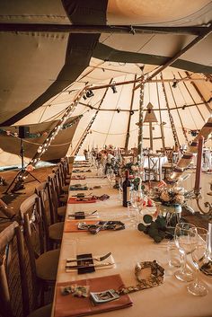 a table set up with wine glasses and place settings in a yurt style tent