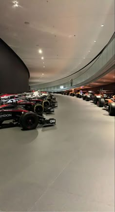 many race cars are lined up in a large room with high ceilings and lights on the ceiling