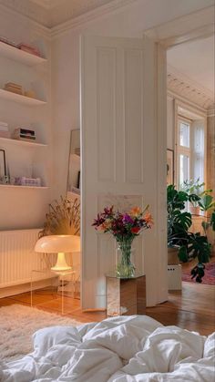 a bedroom with white walls and flooring has flowers in a vase on the bed