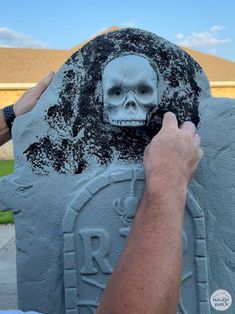 someone is carving a skull on a cement block