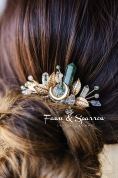 a close up view of a woman's hair wearing a gold and green brooch