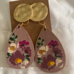 a pair of wooden earrings with flowers painted on them