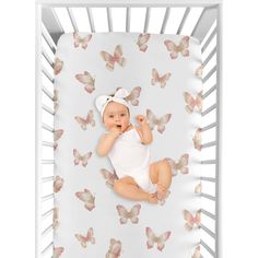 a baby laying in a crib with butterflies on it