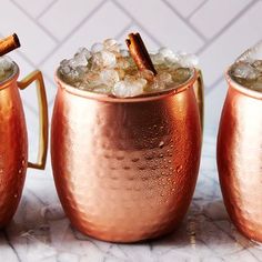 three copper mugs filled with ice and cinnamon sticks