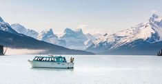 a boat floating on top of a large body of water surrounded by snow covered mountains