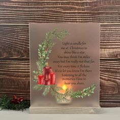 a lighted christmas card with two red candles and evergreen leaves on it next to a pine cone