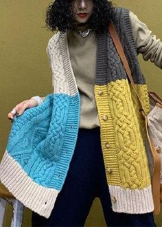 a woman with curly hair wearing a multicolored cardigan and holding a purse