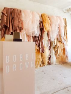 there is a sign that says bobbi brown in front of some clothes hanging on the wall