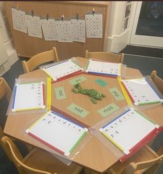 a table with several pieces of paper on top of it and a toy alligator in the middle